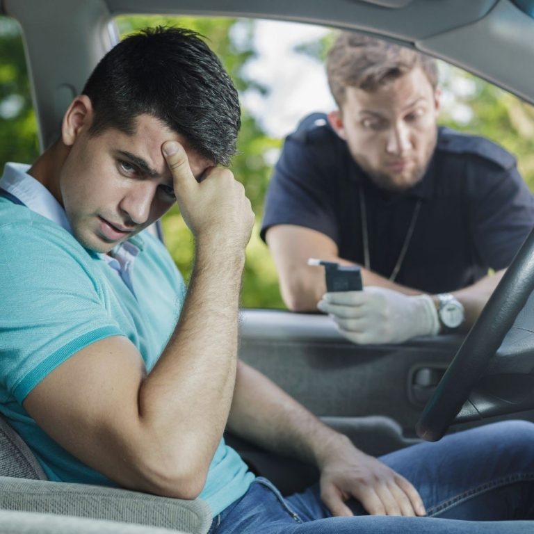 Young police officer holding a portable breathalyzer at a DUI stop